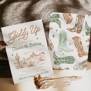 K&ouml;nnte beinhalten: Eine hellgr&uuml;ne und braune Einladung mit Western-Thema. Die Einladung lautet "Giddy Up and join us to celebrate Oliver's 4th Birthday". Die Einladung enth&auml;lt auch eine Zeichnung einer W&uuml;stenlandschaft mit Kakteen und Bergen. Der Text enth&auml;lt Datum, Uhrzeit, Ort und RSVP-Informationen.