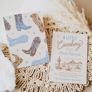 Op de afbeelding: Een uitnodiging voor een babyshower met een patroon van blauwe en bruine cowboylaarzen aan de voorkant en een woestijnsc&egrave;ne met de tekst "A Little Cowboy" aan de achterkant. De uitnodiging bevat de tekst "Saturday, April 22, from 3-6pm, Houston Country Club, 1 Potomac Bt. Houston, TX, RSVP Kaylee 123-456-7890, Registered at babylist.com/karlie.edwards"