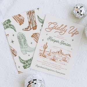 May include: Giddy Up Baby Shower invitation with a western theme. The invitation features a lasso design, a cactus, and a desert landscape. The text reads "Giddy Up" and "Join us for a Baby Shower honouring Harper Jensen".