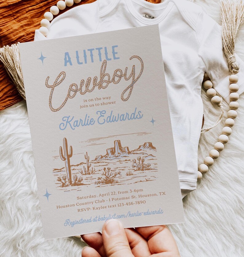 Op de afbeelding: Een lichtbruine uitnodiging met een blauw en bruin touwontwerp met de tekst "A Little Cowboy" en een illustratie van een westelijk landschap. De uitnodiging is voor een babyshower voor Karlie Edwards. De tekst luidt: "Zaterdag 22 april, van 15:00 tot 18:00 uur, Houston Country Club, 1 Potomac St. Houston, TX, RSVP: Kaylee text 123-456-7890, Geregistreerd bij babulist.com/karlie-edwards"