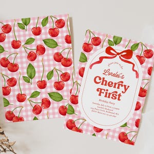 May include: Two invitation cards with a pink gingham pattern and red cherries. One card features the text "Lorelei's Cherry First Birthday Party" in red. The cards are designed for a birthday celebration.