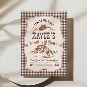 Op de afbeelding: Een rechthoekige uitnodigingskaart met een bruin-witte vichy-ruitrand. In het midden staat de tekst "Saddle Up, Y'all", "Kayce's Fourth Rodeo" en "Wear Your Best Western Gear" met een cowboyhoed en een persoon op een paard.