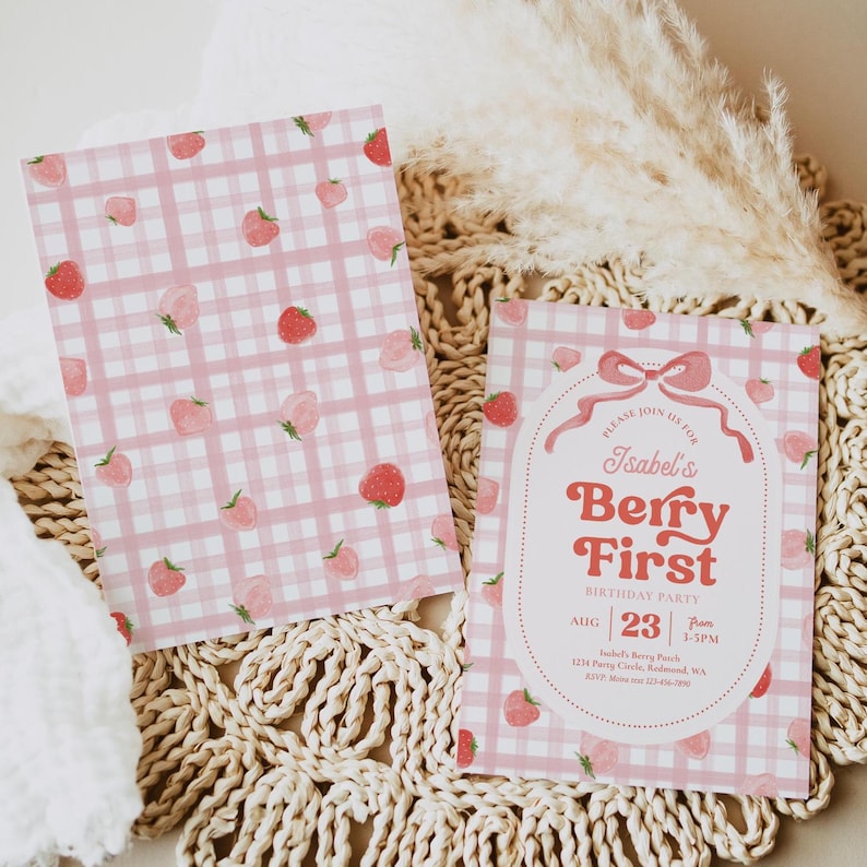 Peut inclure: Deux cartes &agrave; motif vichy rose et blanc avec des illustrations de fraises. L'une est une invitation d'anniversaire avec le texte "Isabel's Berry First Birthday Party" et les d&eacute;tails de l'&eacute;v&eacute;nement.
