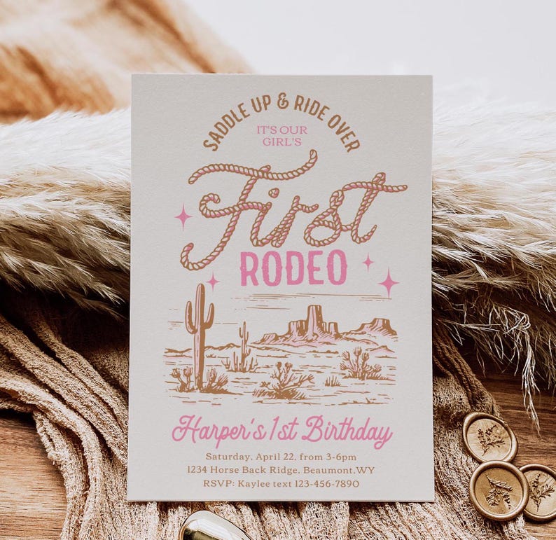 May include: A pink and brown invitation for a first rodeo themed birthday party. The invitation features a hand-drawn illustration of a desert landscape with cacti and mountains. The text reads "Saddle Up & Ride Over It's Our Girl's First Rodeo Harper's 1st Birthday Saturday, April 22, from 3-6pm 1234 Horse Back Ridge, Beaumont, WY RSVP: Kaylee text 123-456-7890"