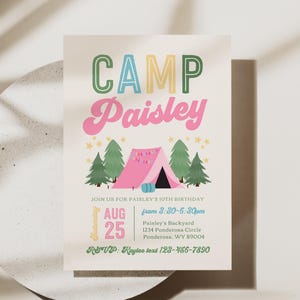 May include: A rectangular invitation card with a cream background featuring the text CAMP Paisley in green, blue, and pink. Below, a pink tent is surrounded by green pine trees and yellow stars. Details include date, time, and location for a 10th birthday.