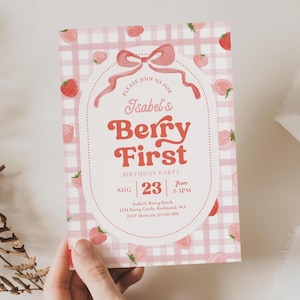 Peut inclure: Une invitation &agrave; motif vichy rose et blanc avec des illustrations de fraises. Le texte indique "Isabel's Berry First Birthday Party" avec la date du 23 ao&ucirc;t et l'heure de 15h &agrave; 17h. Un n&oelig;ud et une bordure pointill&eacute;e encadrent le texte.