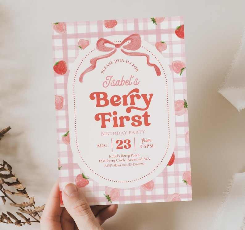 Peut inclure: Une invitation &agrave; motif vichy rose et blanc avec des illustrations de fraises. Le texte indique "Isabel's Berry First Birthday Party" avec la date du 23 ao&ucirc;t et l'heure de 15h &agrave; 17h. Un n&oelig;ud et une bordure pointill&eacute;e encadrent le texte.