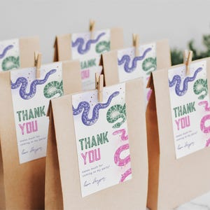 May include: Brown paper bags with thank you tags featuring a purple and green snake design. The tags say "Thank You" and have a message that reads "Thank you so much for coming to my party!"