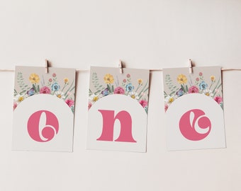May include: Three white cards with floral borders and pink letters spelling out the word "one".