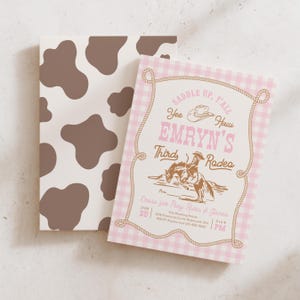 May include: Two rectangular invitation cards. One features a brown and white cow print pattern. The other has a pink and white gingham background with a rope border, a cowboy hat icon, and text reading: SADDLE UP, Y'ALL, EMRYN'S THIRD RODEO.