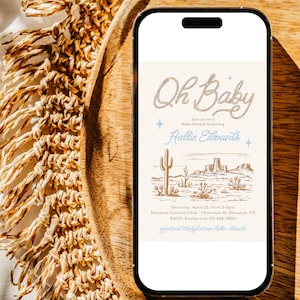 May include: A digital invitation for a baby shower with a desert landscape background. The text reads "Oh Baby" with a rope design and "Join us for a Baby Shower honoring Hallie Edwards". The invitation includes the date, time, location, and RSVP information.