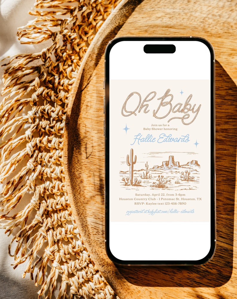 May include: A digital invitation for a baby shower with a desert landscape background. The text reads "Oh Baby" with a rope design and "Join us for a Baby Shower honoring Hallie Edwards". The invitation includes the date, time, location, and RSVP information.
