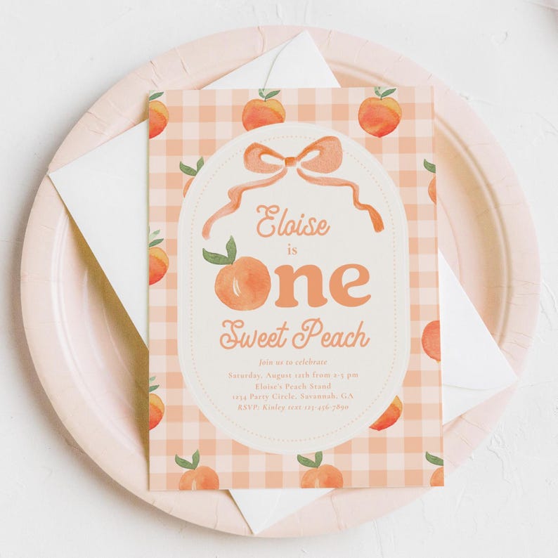 May include: A peach-themed invitation card with the text "Eloise is one Sweet Peach" in a decorative oval. The card has a peach gingham pattern and peach illustrations. The invitation is on a pink plate with a white envelope.