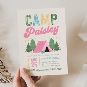 May include: A rectangular invitation card with a cream background featuring the text CAMP Paisley in green, blue, and pink. Below is a pink tent, green pine trees, and yellow stars. Text includes JOIN US FOR PAISLEY'S 10TH BIRTHDAY, AUG 25, and address.