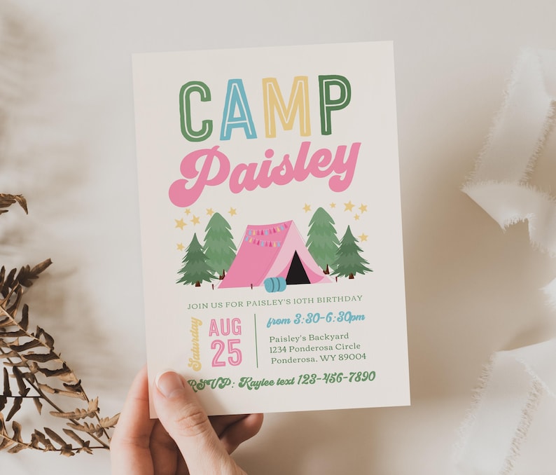 May include: A rectangular invitation card with a cream background featuring the text CAMP Paisley in green, blue, and pink. Below is a pink tent, green pine trees, and yellow stars. Text includes JOIN US FOR PAISLEY'S 10TH BIRTHDAY, AUG 25, and address.