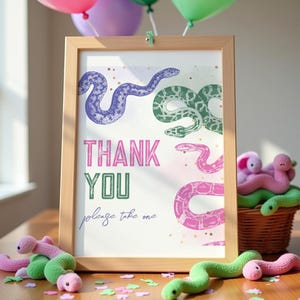 Könnte beinhalten: Ein gerahmtes Dankeschön-Schild mit einem Schlangenmuster in Pink, Grün und Lila. Das Schild sagt "Danke" und "Bitte nehmen Sie eins".