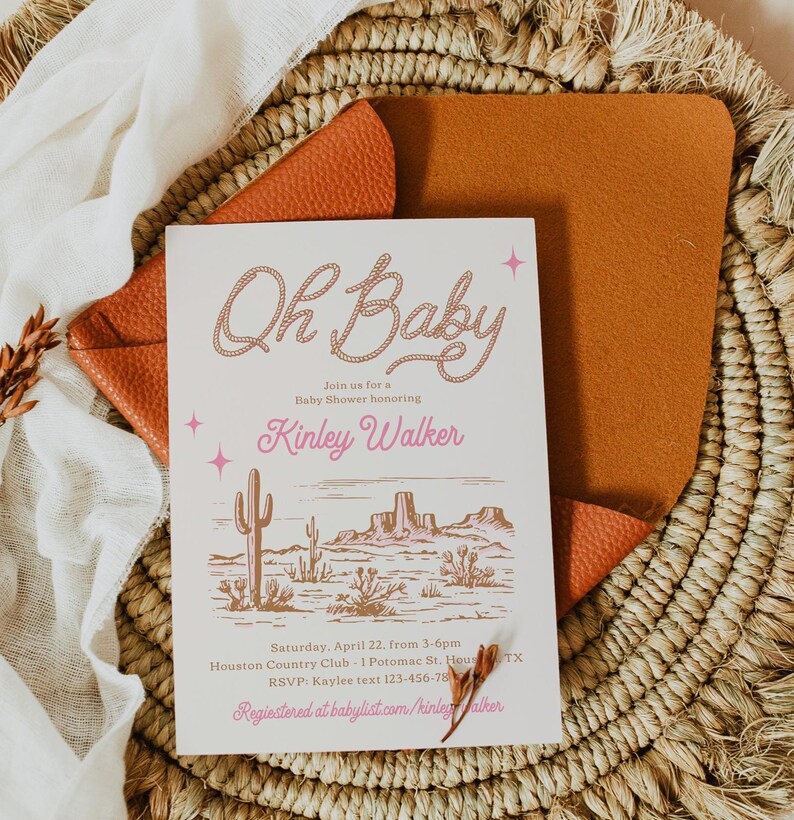 May include: A pink and brown baby shower invitation with a western theme. The invitation says "Oh Baby" in a pink rope design and "Kinley Walker" in pink lettering. The invitation also includes a desert landscape illustration with cacti and mountains.
