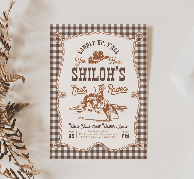 Op de afbeelding: Een rechthoekige uitnodigingskaart met een bruin-witte vichy-ruitrand. Het midden toont een touwframe met de tekst "Saddle Up, Y'all", "Yee Haw", "Shiloh's First Rodeo" en "Wear Your Best Western Gear" met een cowboy op een paard.