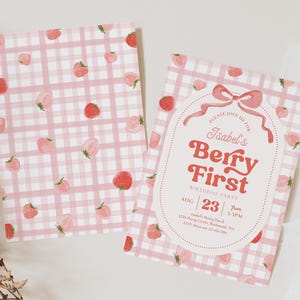 Peut inclure: Deux invitations &agrave; carreaux roses et blancs avec des illustrations de fraises. L'une porte le texte "Isabel's Berry First Birthday Party" avec la date et l'heure. L'autre a un motif de fraises.