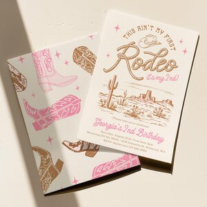 May include: Two rectangular birthday invitation cards featuring a western theme with pink and brown illustrations of cowboy boots, cacti, and stars. The text reads: This Ain't My First Rodeo it's my 2nd! Georgia's 2nd Birthday, date, and location.