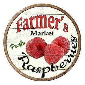 May include: Round wooden sign with a white background and a brown wooden frame. The sign reads "Farmer's Market" in red, with "Fresh" in green and "Raspberries" in black. Three red raspberries are featured in the center.