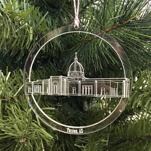 May include: Clear acrylic Christmas ornament featuring a detailed architectural outline of a building with a dome, likely a government building or church. The ornament is circular with the text "Tucson, AZ" at the bottom, and is suspended by a red and white string.