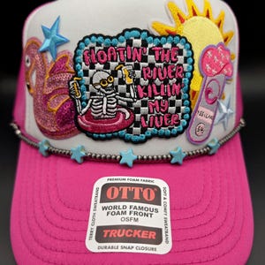 May include: A white ceramic mug with a black handle and the text "But First, Coffee" in a bold, black font. The mug is set against a blurred background, suggesting a cozy setting.