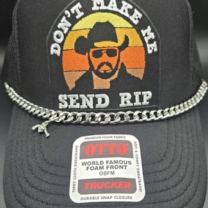 May include: Black trucker hat with a silver chain and a patch that says "Don't Make Me Send Rip" with a cartoon cowboy wearing sunglasses. The patch has a sunset graphic with orange, yellow, and red stripes. The hat has a black mesh back and a black front with a white label that says "Otto World Famous Foam Front OSFM Trucker Durable Snap Closure".
