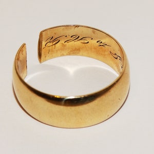 Pode incluir: Um anel de banda de ouro com uma inscrição no interior. A inscrição diz "25. 25. ou 5."