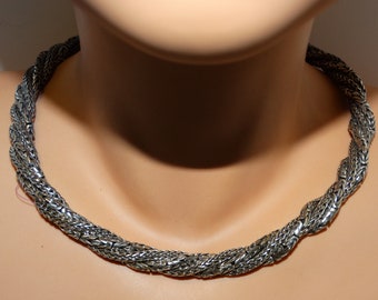 Puede incluir: Un collar de cadena de plata con un diseño trenzado.