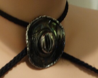 Op de afbeelding: Een zwarte koordketting met een zilveren cowboyhoed-hanger van abalone-schelp.