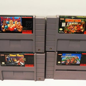 Könnte beinhalten: Vier Super Nintendo Entertainment System-Spielkassetten: Super Punch-Out!!, Donkey Kong Country, Stunt Race FX und Super Mario Kart.