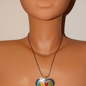 May include: A silver necklace with a heart-shaped pendant. The pendant is decorated with a swirling pattern and the word "LOVE" in colorful enamel.