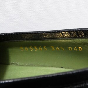 May include: Close-up of the inside of a black leather shoe with a green lining. The size 36 1/2 is printed in gold on the lining.