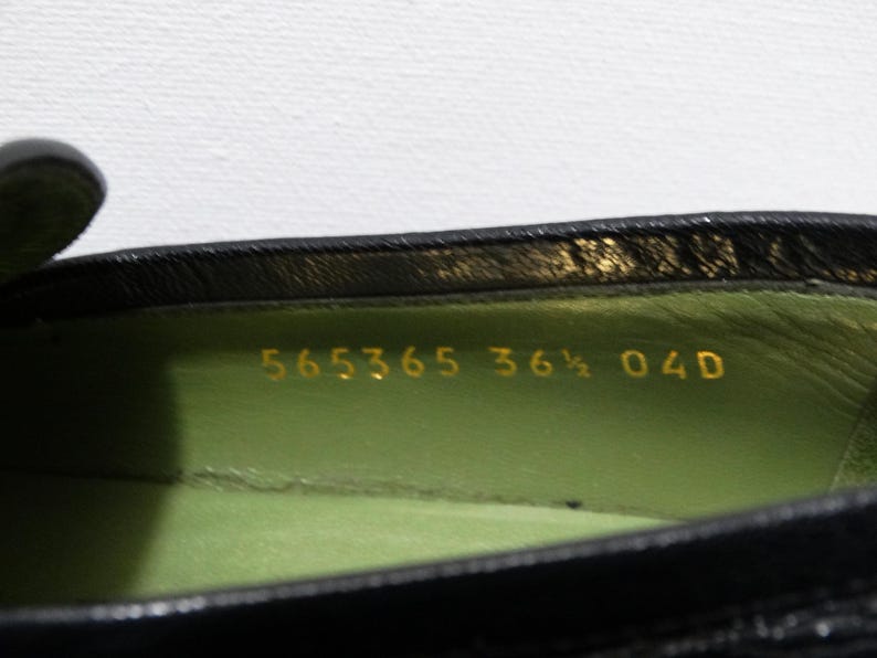 May include: Close-up of the inside of a black leather shoe with a green lining. The size 36 1/2 is printed in gold on the lining.