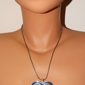 May include: A silver chain necklace with a heart-shaped pendant. The pendant is blue with a silver border and features the word "LOVE" in colorful enamel letters.