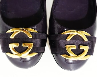Könnte beinhalten: Paar violette Lackballerinas mit goldenen, ineinander verschlungenen GG-Logo-Verzierungen an der Spitze.