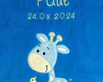 Puede incluir: Una manta de bebé azul con una jirafa azul claro y un pájaro amarillo bordados. La manta está personalizada con el nombre "Paul" y la fecha "24.03.2024".