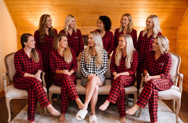 A group of women wearing red and black plaid pajamas are sitting together, smiling and posing for a photograph.