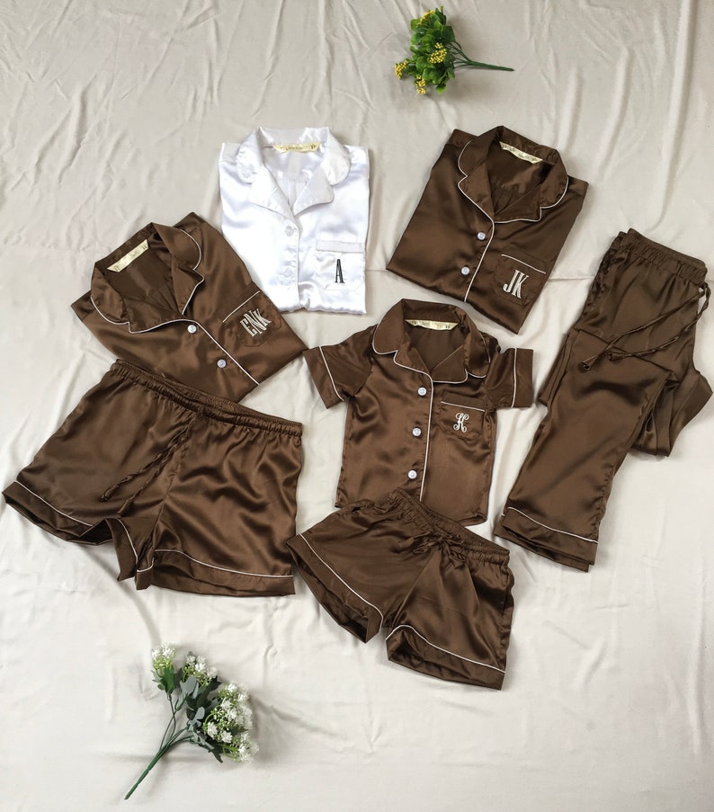 K&ouml;nnte beinhalten: Ein Set aus braunen Satin-Pyjamas mit wei&szlig;en Paspeln und gestickten Initialen. Das Set beinhaltet ein Langarmshirt, ein Kurzarmhemd, eine kurze Hose und eine lange Hose.