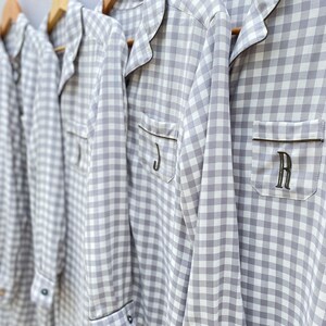 May include: Four gray and white gingham pajamas with black trim and personalized initials. The initials are J, R, and two others.