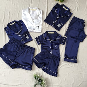 K&ouml;nnte beinhalten: Ein passendes Pyjama-Set in Marineblau und Wei&szlig;. Der Pyjama besteht aus einem Oberteil mit Kn&ouml;pfen und kurzen &Auml;rmeln sowie einem gestickten Initial auf der Tasche. Das Set enth&auml;lt eine kurze Hose und eine lange Hose.