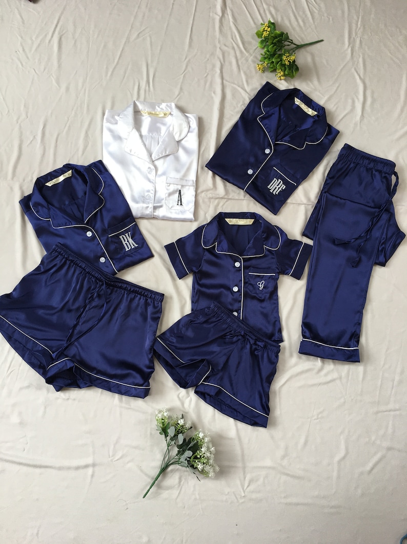 K&ouml;nnte beinhalten: Ein passendes Pyjama-Set in Marineblau und Wei&szlig;. Der Pyjama besteht aus einem Oberteil mit Kn&ouml;pfen und kurzen &Auml;rmeln sowie einem gestickten Initial auf der Tasche. Das Set enth&auml;lt eine kurze Hose und eine lange Hose.