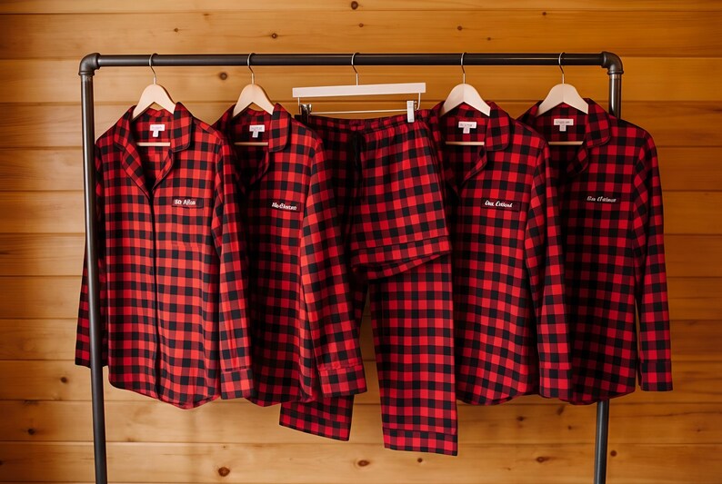 A row of red and black plaid pajamas hanging on a rack, with each pair having a name tag attached to the front.