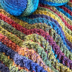 May include: Two balls of yarn in a multi-colored striped pattern. The yarn is a mix of blue, green, orange, and red.