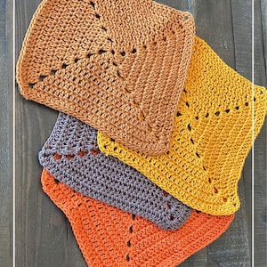Peut inclure: Quatre torchons en crochet dans des tons d'orange, de brun et de jaune. Les torchons sont empilés les uns sur les autres, le torchon orange en bas et le torchon jaune en haut. Les torchons sont faits avec un motif de point simple et ont une forme carrée.