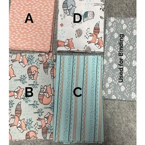 Puede incluir: Un conjunto de cuatro paquetes de tela de tama&ntilde;o "fat quarter" con un tema de zorro y bosque. Las telas incluyen un estampado de lunares rosa y blanco, una tela blanca con un estampado de zorro y criaturas del bosque, una tela a rayas azul y blanca y una tela gris con un estampado de hongos. Las telas est&aacute;n etiquetadas como A, B, C y D. La tela gris est&aacute; etiquetada como "Used for Binding".