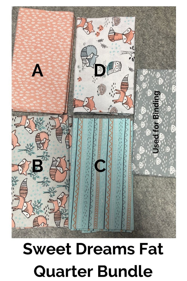 Puede incluir: Un conjunto de cuatro paquetes de tela de tama&ntilde;o "fat quarter" con un tema de zorro y bosque. Las telas incluyen un estampado de lunares rosa y blanco, una tela blanca con un estampado de zorro y criaturas del bosque, una tela a rayas azul y blanca y una tela gris con un estampado de hongos. Las telas est&aacute;n etiquetadas como A, B, C y D. La tela gris est&aacute; etiquetada como "Used for Binding".