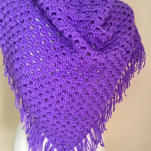 May include: A purple crocheted shawl with fringe. The shawl is made with a delicate open stitch pattern.