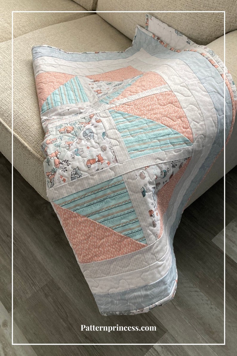 Puede incluir: Una colcha de retazos rosa y azul con un tejido estampado de zorros y b&uacute;hos. La colcha est&aacute; doblada en un sof&aacute; marr&oacute;n claro y un suelo de madera.